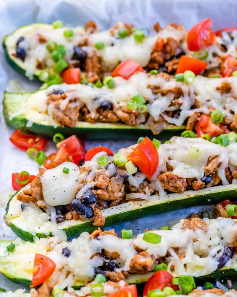 Side view of stuffed zucchini boats with melted cheese and chopped tomatoes