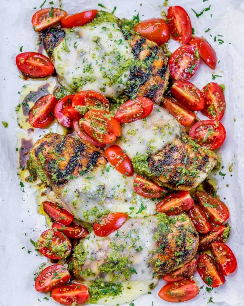 Chicken served with cheese, tomatoes and pesto on a large white serving plate.