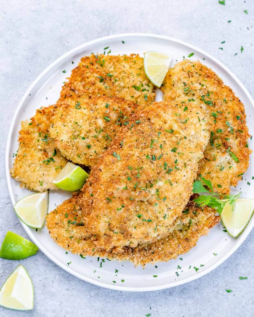 Crispy chicken served with fresh parsley and lime wedges.