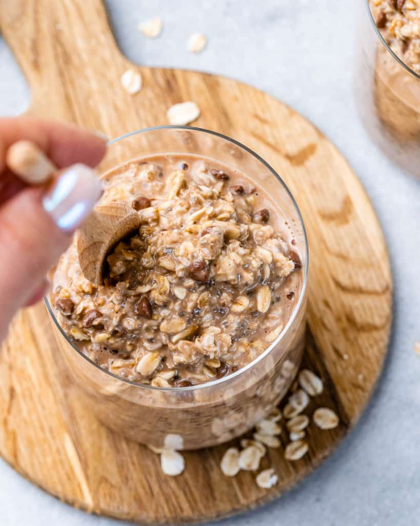 Woman's hand stirring overnight oats in a jar.