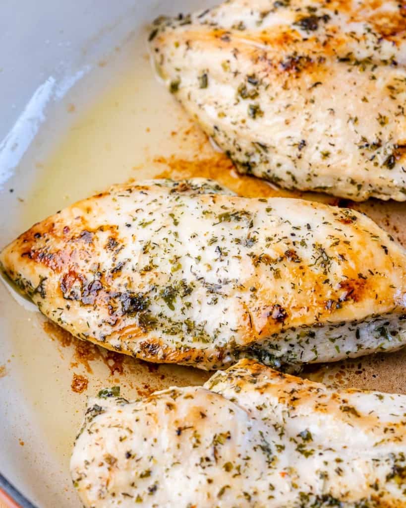 Chicken breast cooking in a skillet.