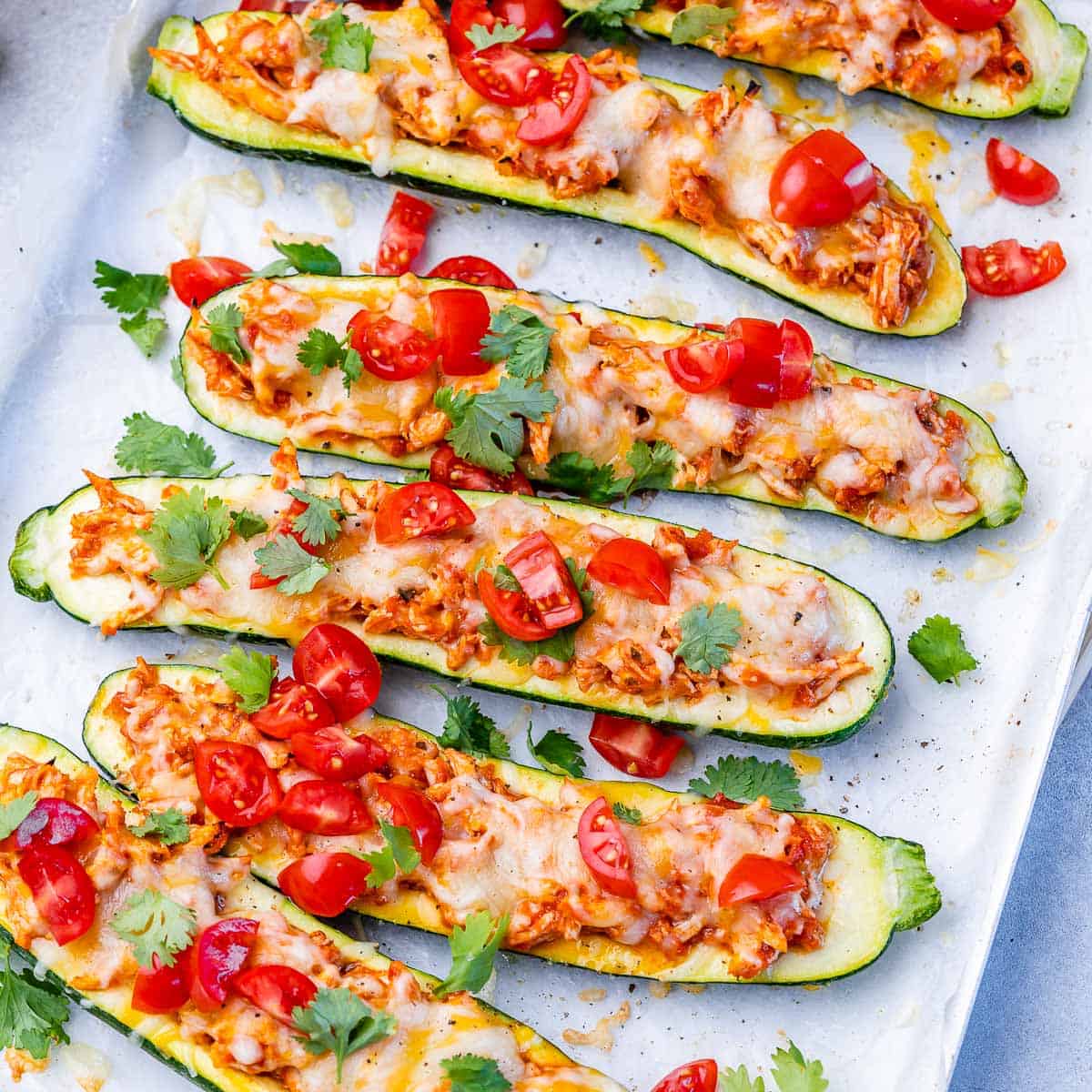 top view zucchini boats topped with chopped tomatoes