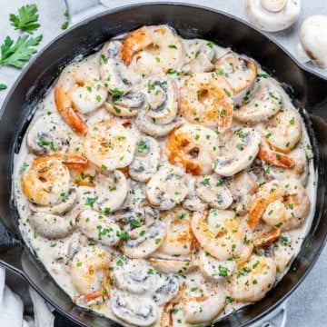 top view of sauteed shrimp in a creamy mushroom sauce in a black skillet