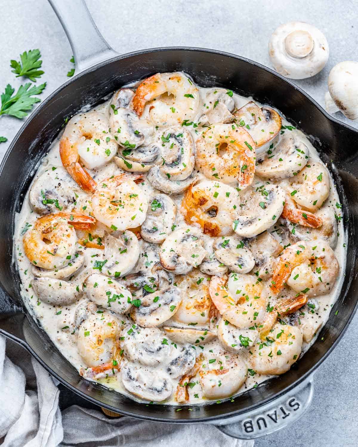 top view of sauteed shrimp in a creamy mushroom sauce in a black skillet