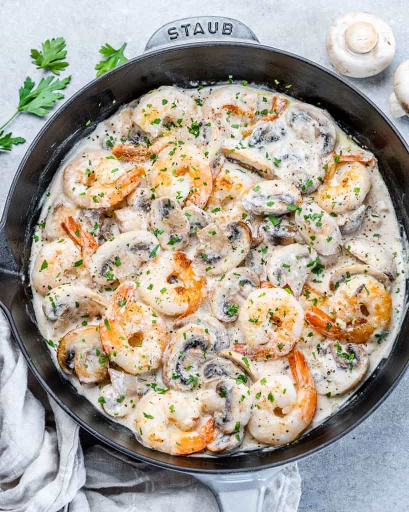 top view creamy shrimp with mushrooms in a black skillet