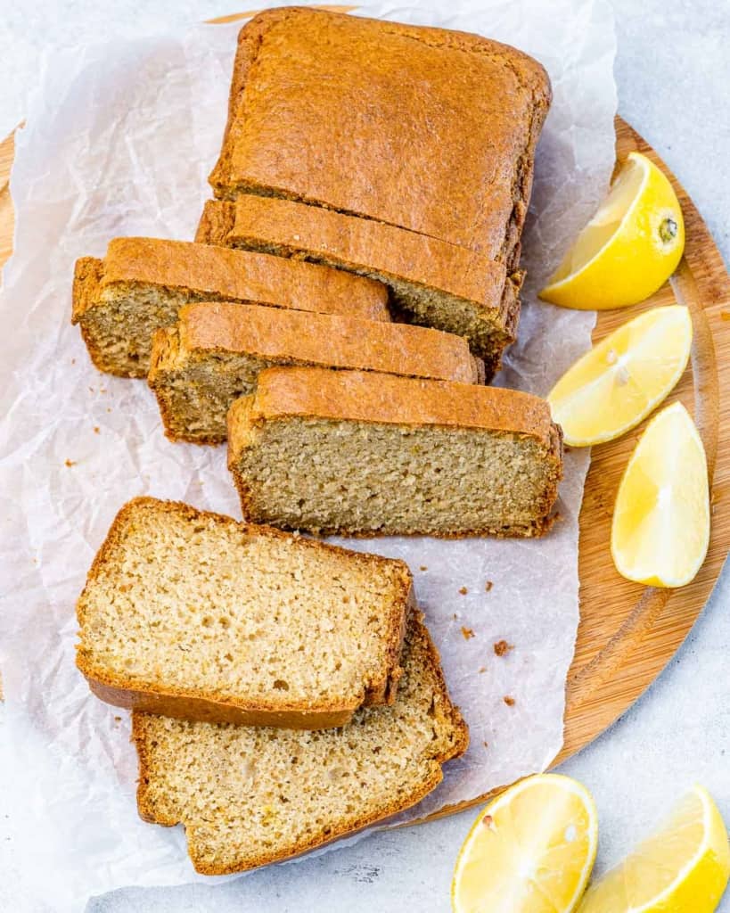 top view of lemon bread slices with fresh lemon slices on the right side of the loaf bread