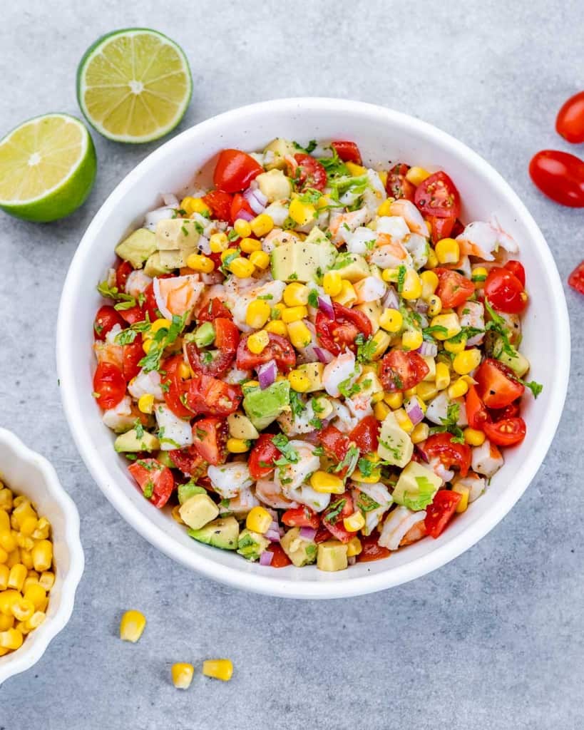 top view of shrimp salad with corn, tomatoes, and avocados, in a white bowl