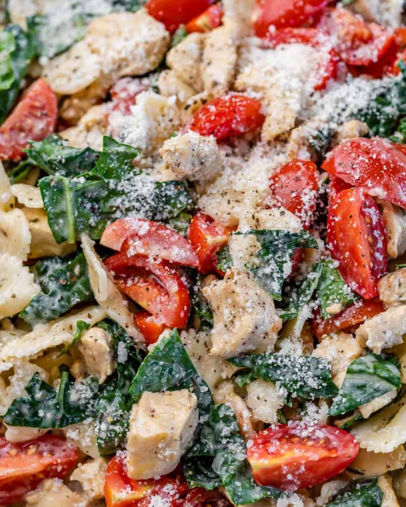 Creamy chicken, pasta, kale and tomatoes in a skillet.