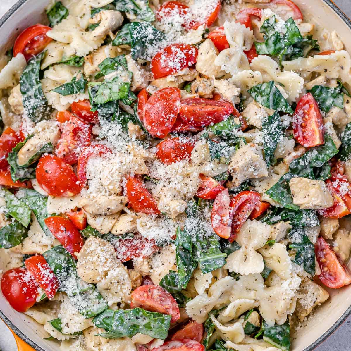 top view of chicken and spinach pasta topped with cheese and tomatoes