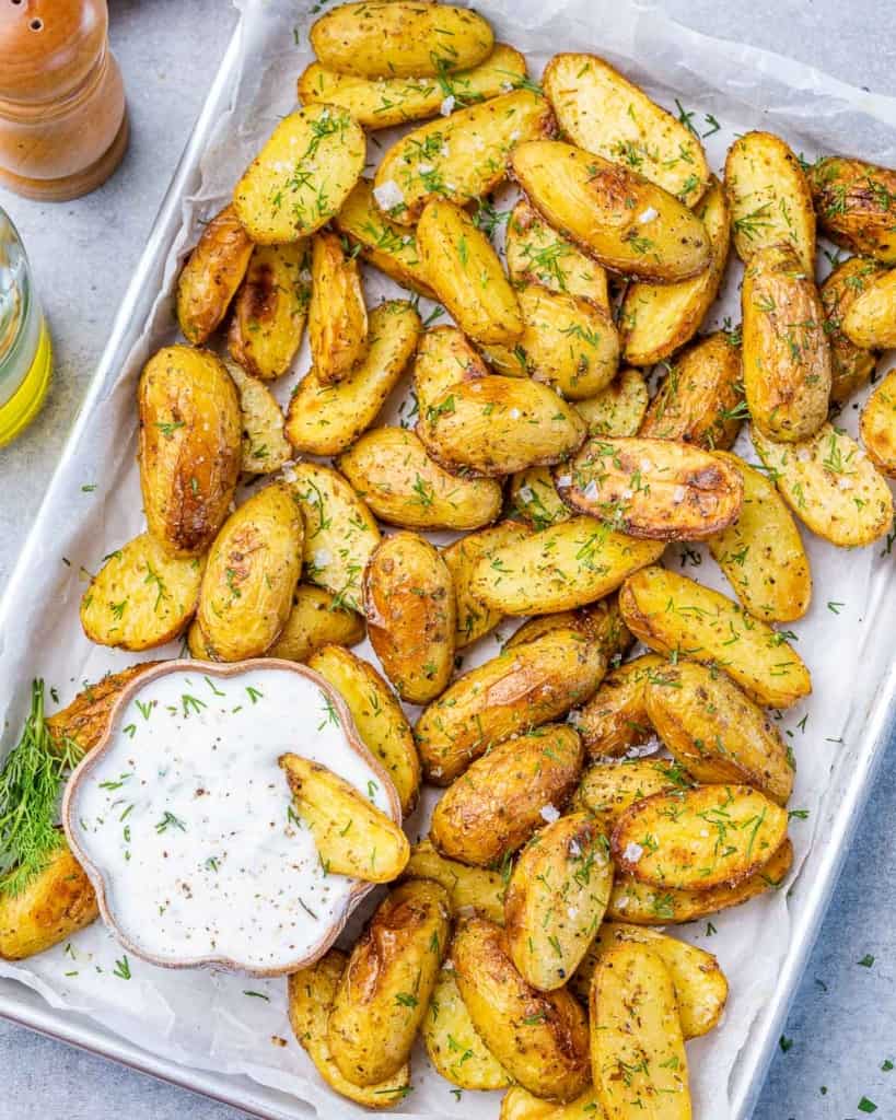 top view of crispy potato wedges on a pan with greek dressing dip