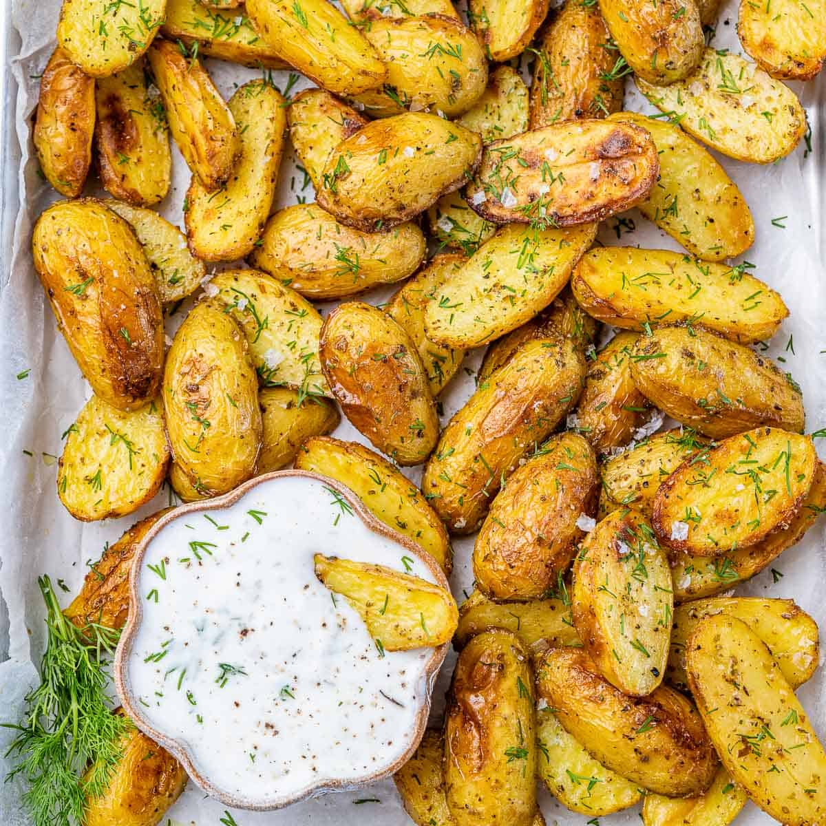 top view of baked potato wedges with a bowl of greek dipping sauce