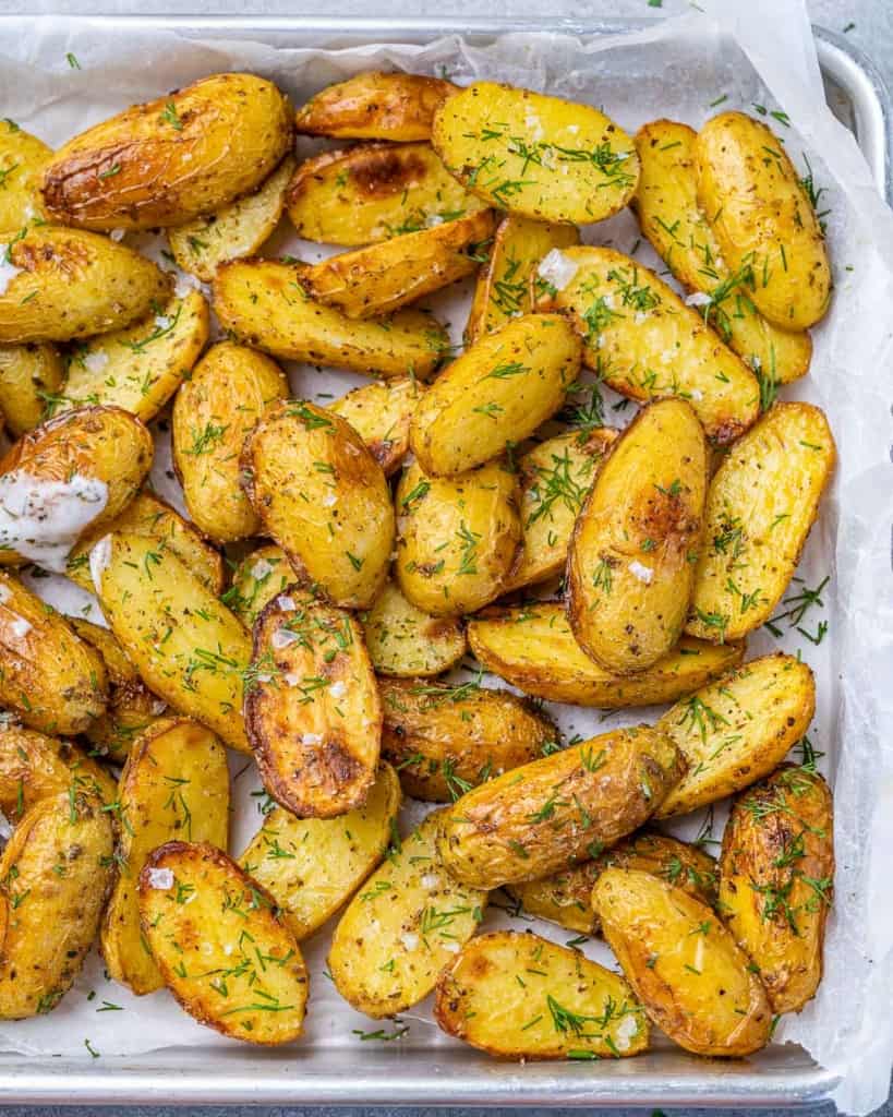 Crispy baked potato wedges on a parchment lined baking sheet.