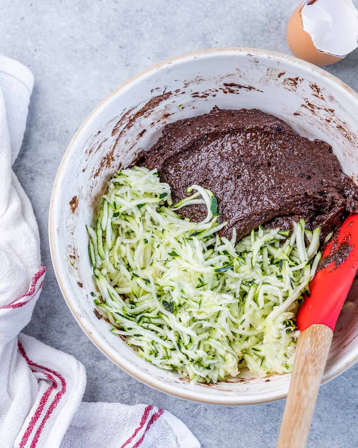 Adding shredded zucchini to chocolate brownie batter.