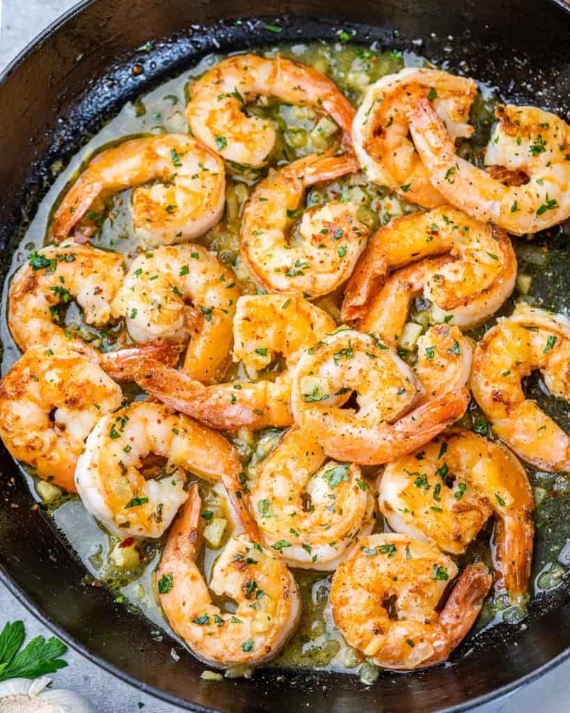 Shrimp cooking in a skillet with olive oil.