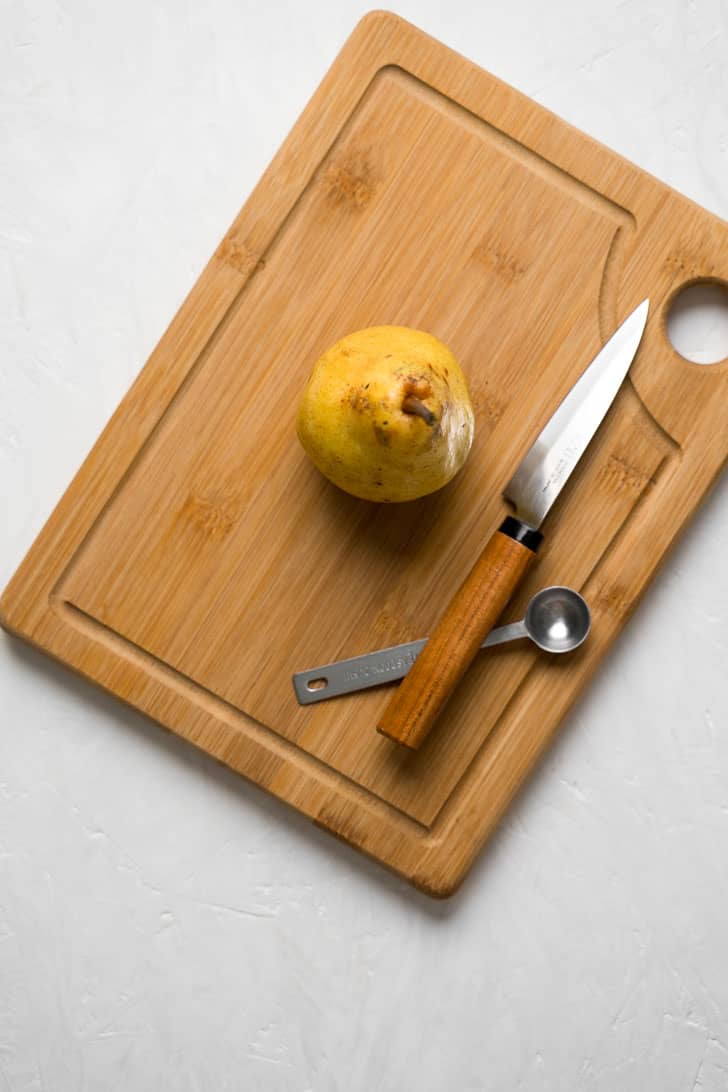 one pear on board with knife and spoon 
