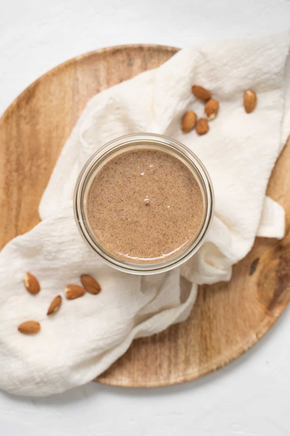 almond butter in glass jar with white linen