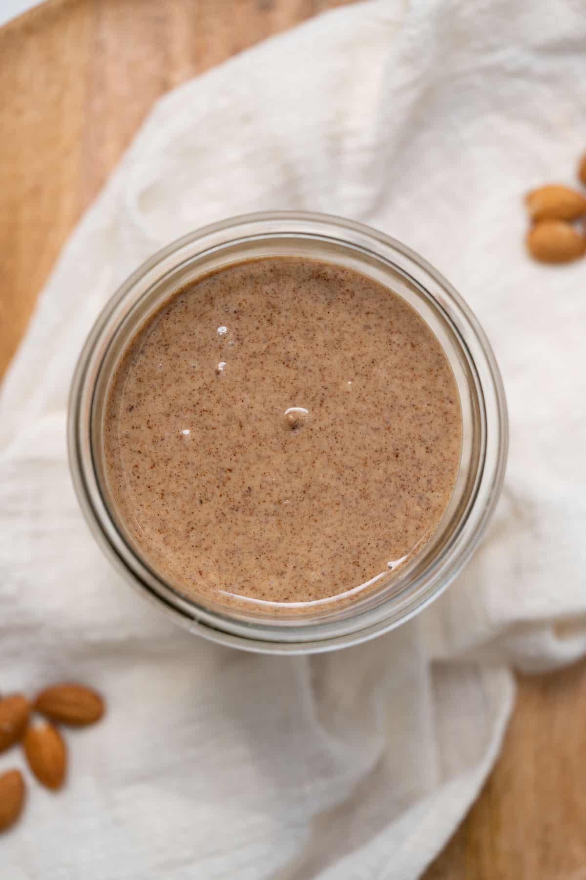 almond butter in glass jar with white linen