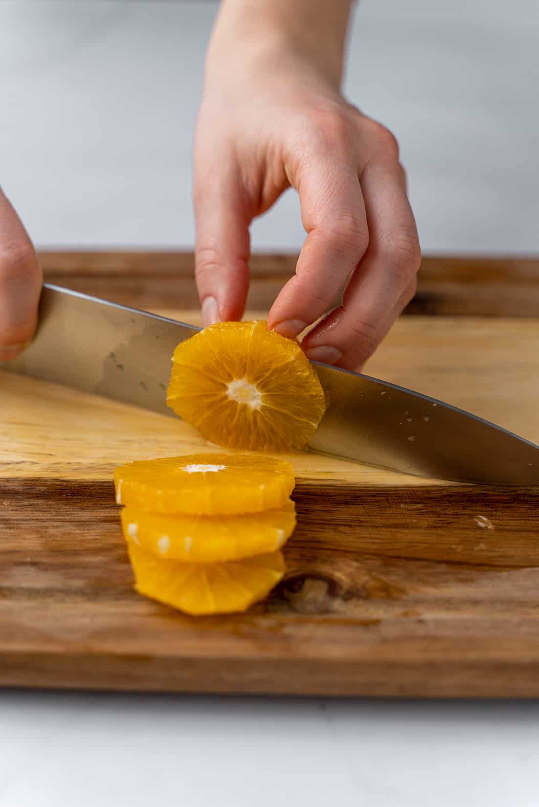 cutting the orange into rings with knife on cutting board