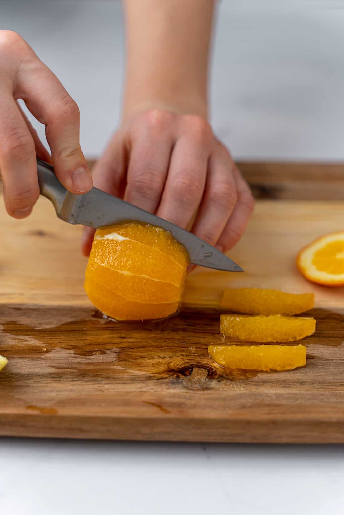 slicing the orange into slices with knife and cutting baord