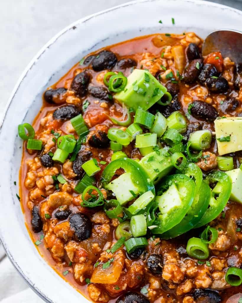 White bowl filled with chili made with black beans.
