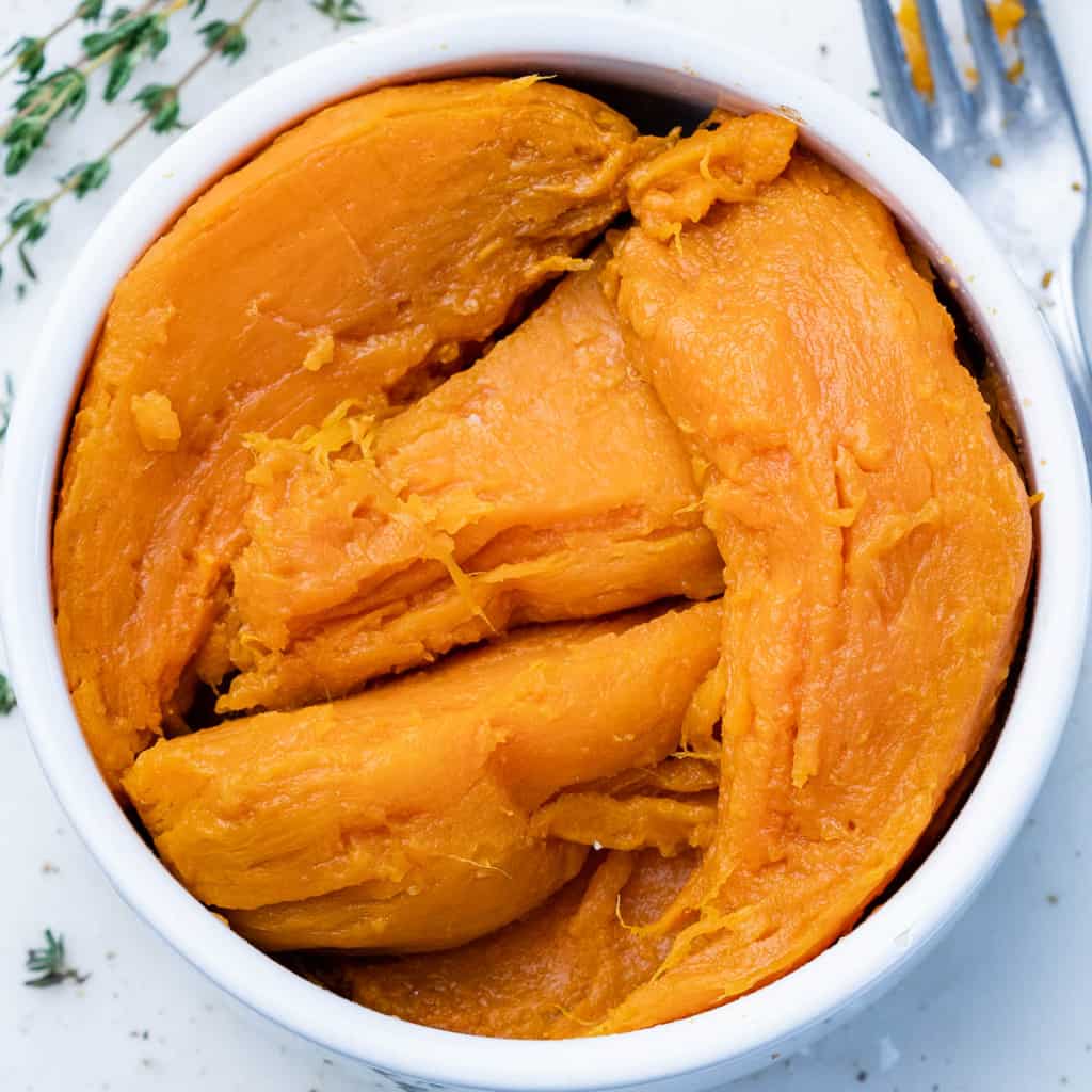 Cooked sweet potatoes without the skin in a white bowl.