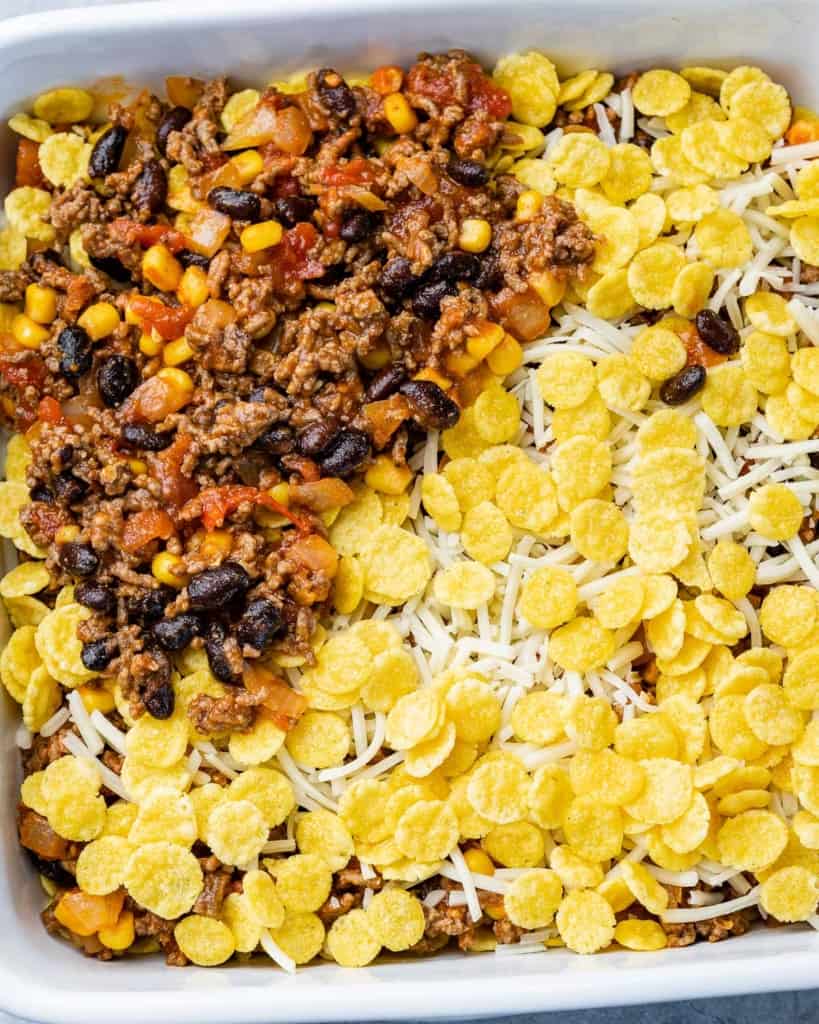 Layering beef mixture, cornflakes and cheese in a baking dish.