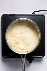 Adding parmesan cheese to homemade Alfredo Sauce.