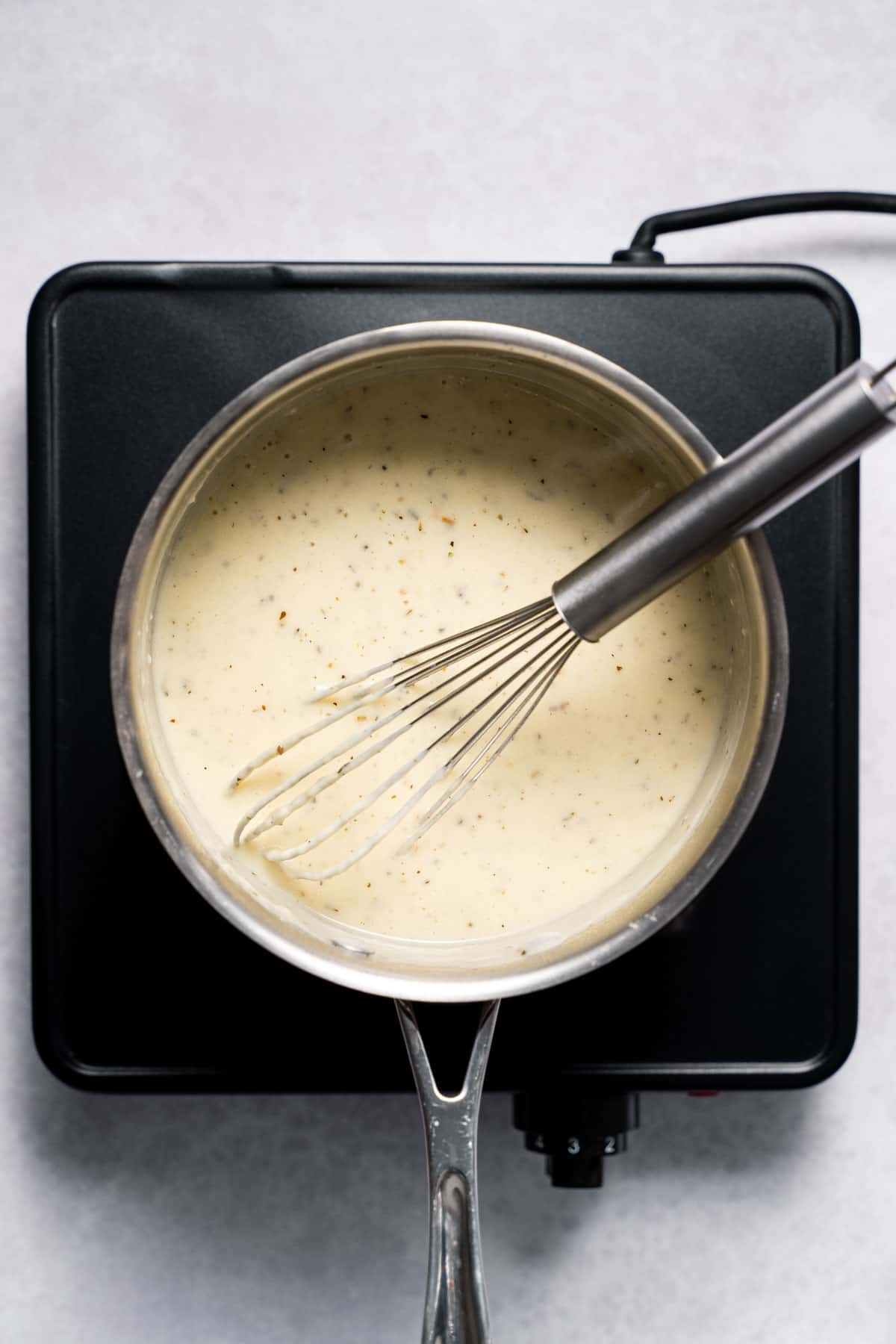 Whisking healthy Alfredo Sauce in a pan.