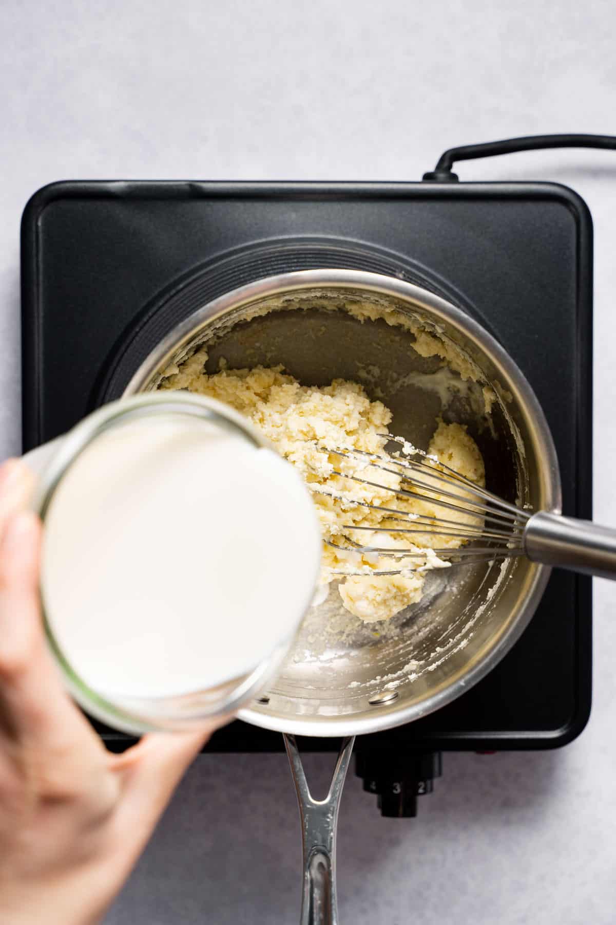 Pouring milk into pan with cream cheese flour mixture.