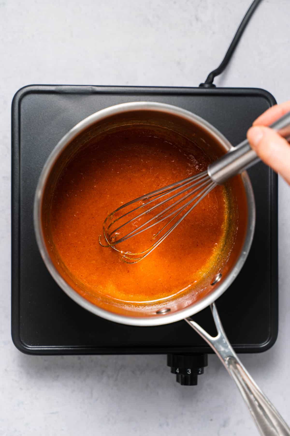 mixing buffalo sauce in saucepan with whisk