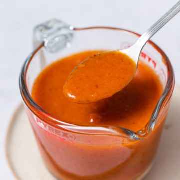 side shot of buffalo sauce in a jar with spoonful of sauce
