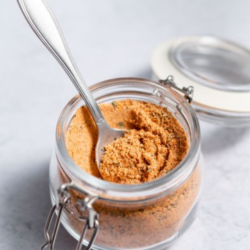 side shot of cajun seasoning in a jar with spoon in it