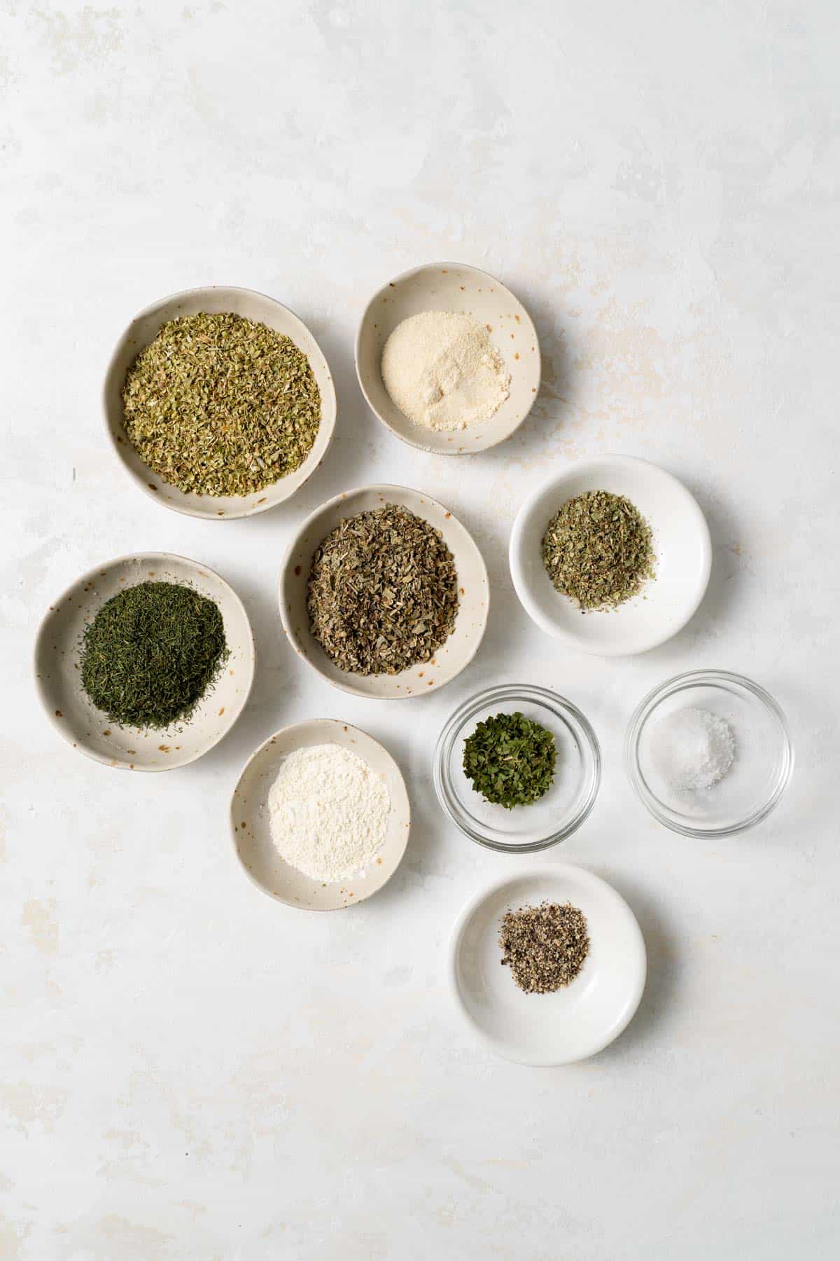 individual spices and herbs in bowls 