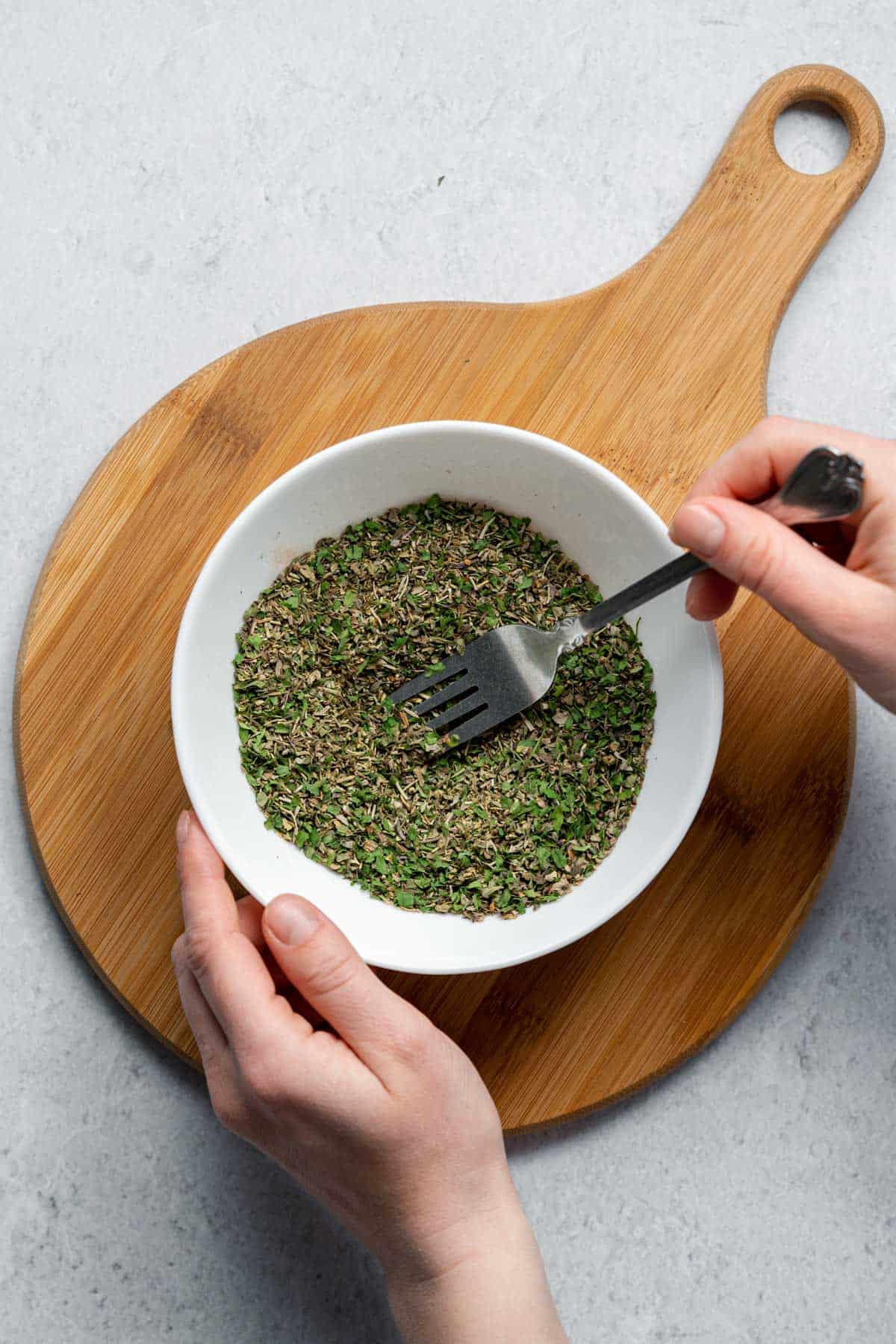 mixing dried herbs with fork in bowl 