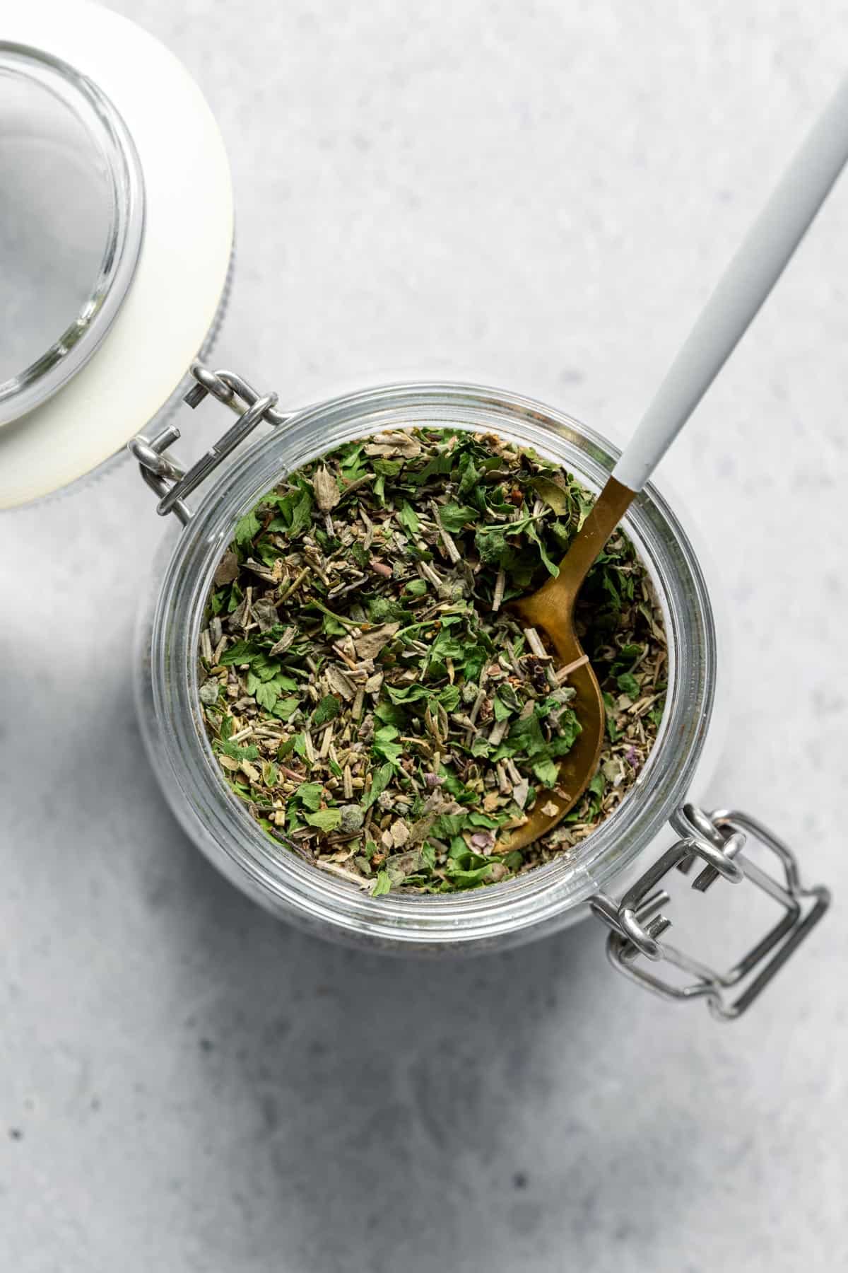 jar filled with dried herbs and spoon 