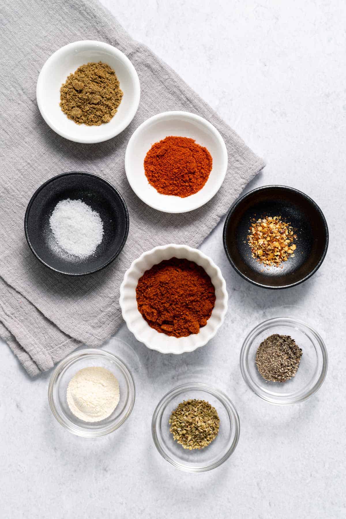 paprika, cumin, chili powder, salt, pepper, chili flakes, oregano in bowls