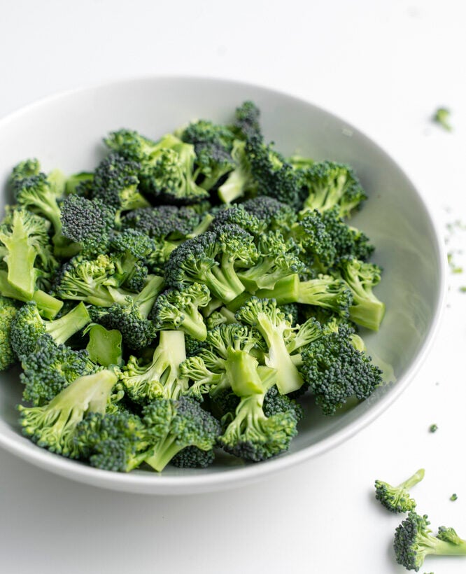 Cut up broccoli in a white bowl.
