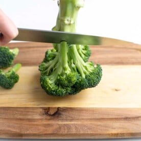 Knife cutting over broccoli stem.