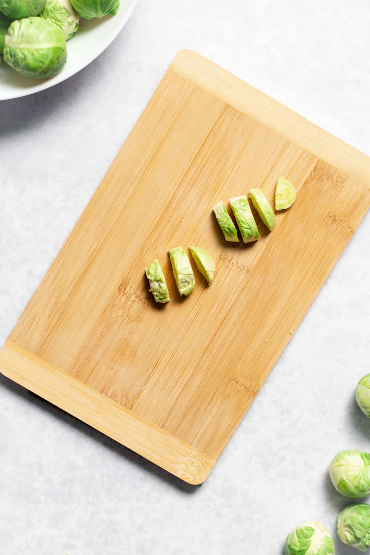 sliced brussels sprouts atop wooden cutting board