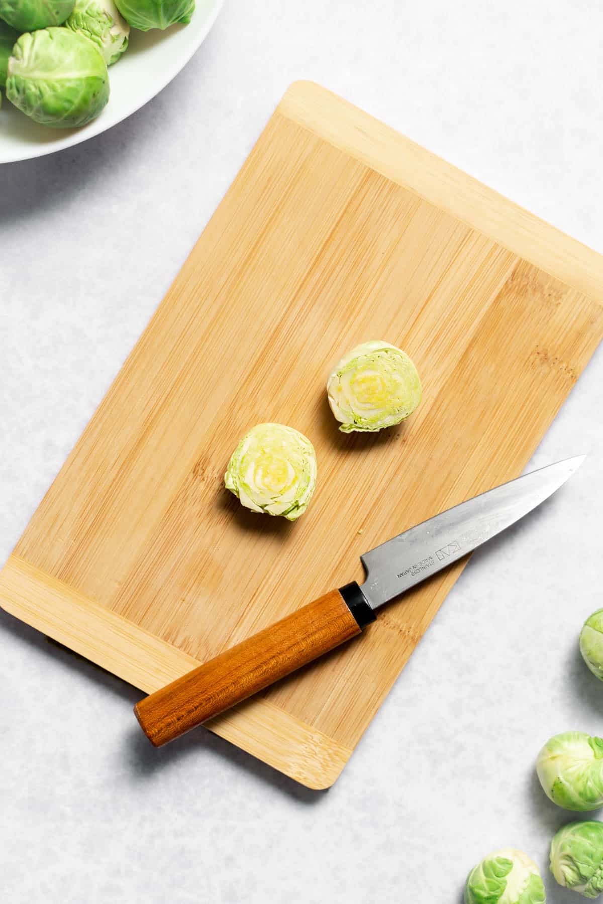 two halves of brussels sprouts on cutting board with knife 