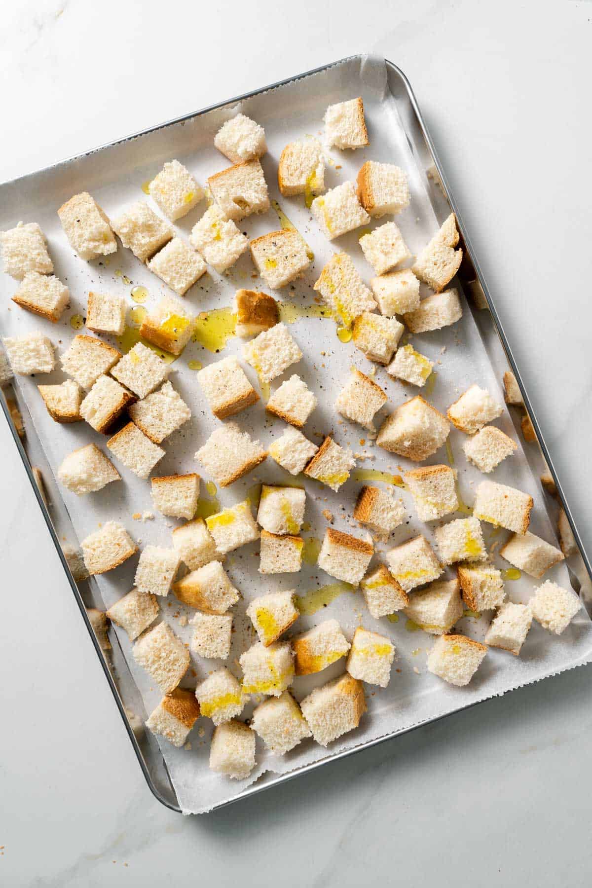 bread cubes tossed with olive oil atop baking sheet 
