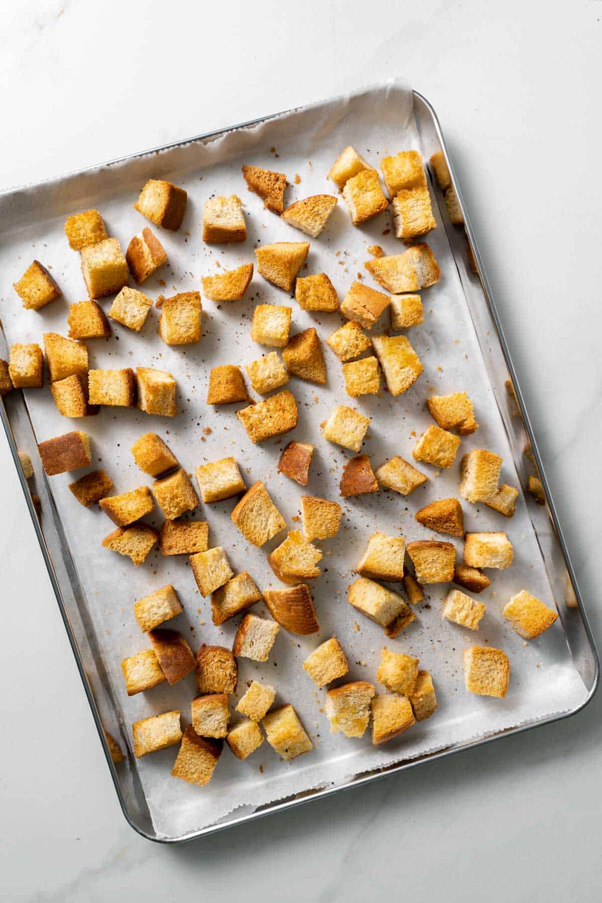 golden baked croutons on baking sheet with parchment paper 