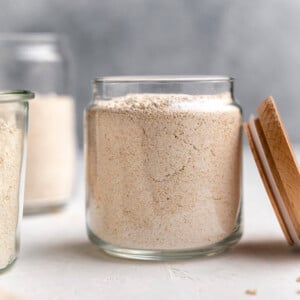 side shot of oat flour in a jar with lid on the right side of it