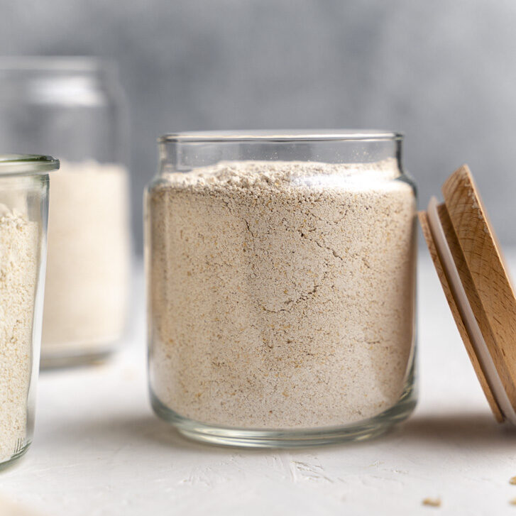 side shot of oat flour in a jar with lid on the right side of it