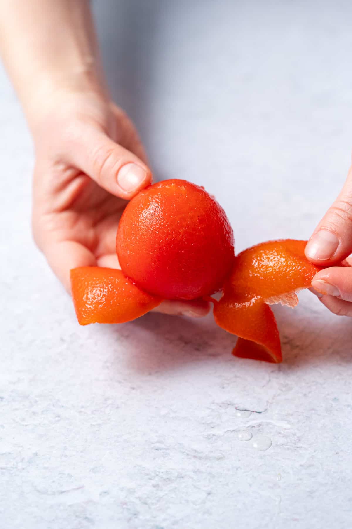 peeling one tomato with hands 