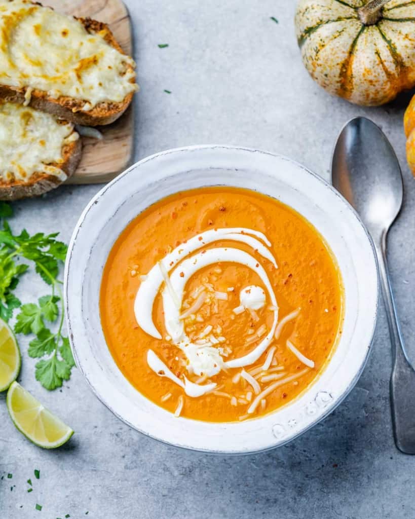 spoon next to a bowl of butternut squash soup in a white bowl