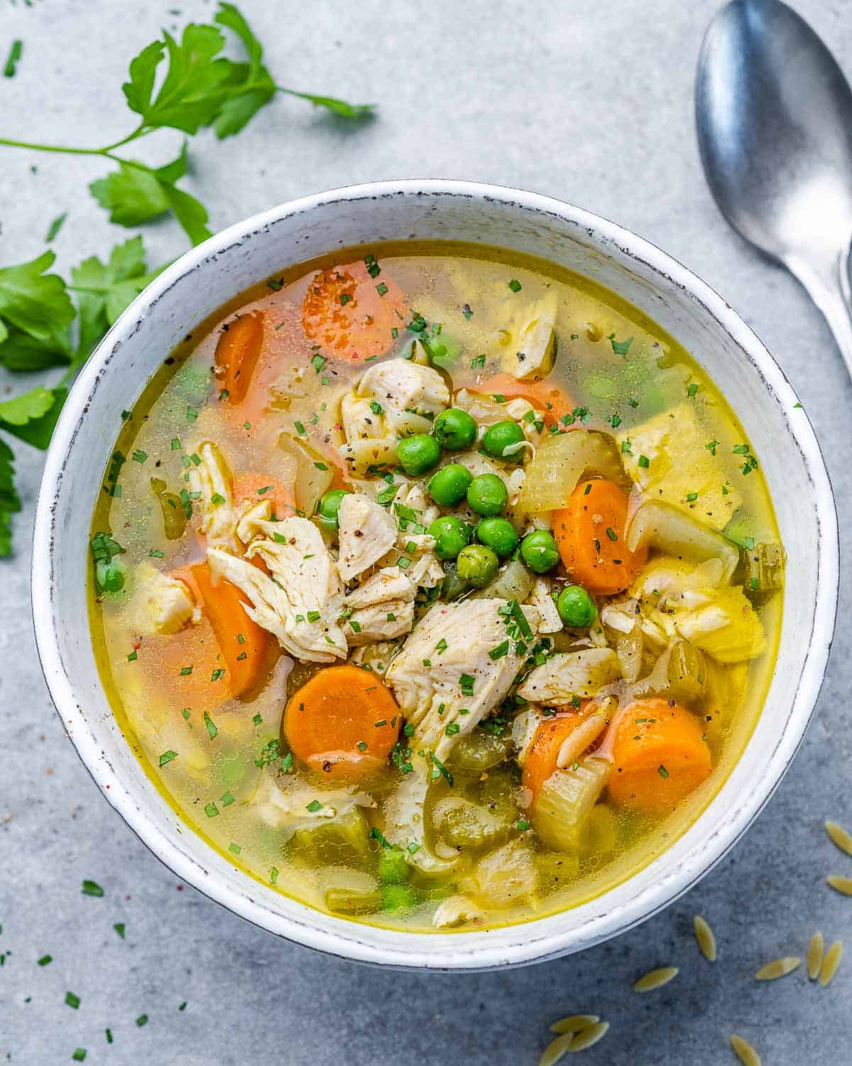 Soup with turkey, carrots and peas in a white bowl.
