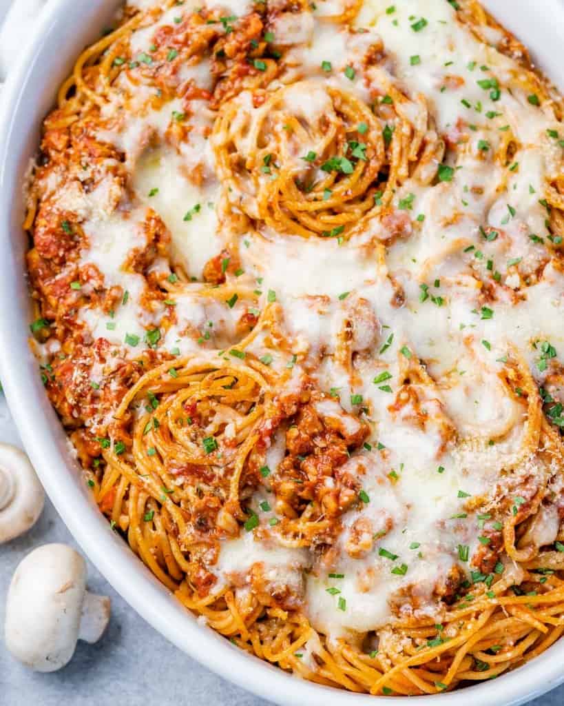 top view of spaghetti topped with melted cheese in a white casserole dish