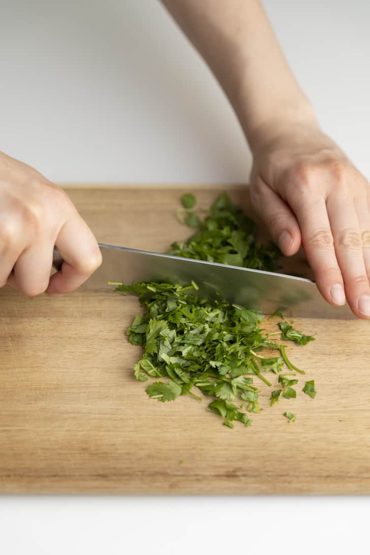 slicing the cilantro atop wooden cutting board