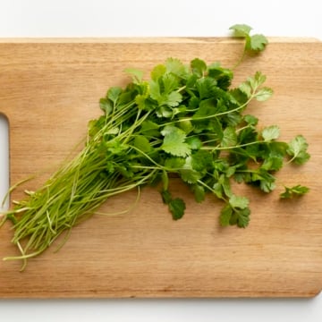 top view image of a bunch of fresh cilantro on a wood cutting board